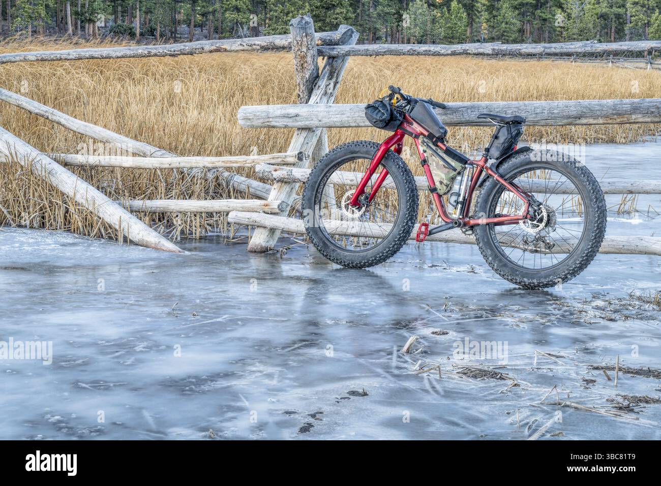 Gros vélo avec sacs de cadre sur le ruisseau couvert de glace dans les montagnes Rocheuses du Colorado Banque D'Images