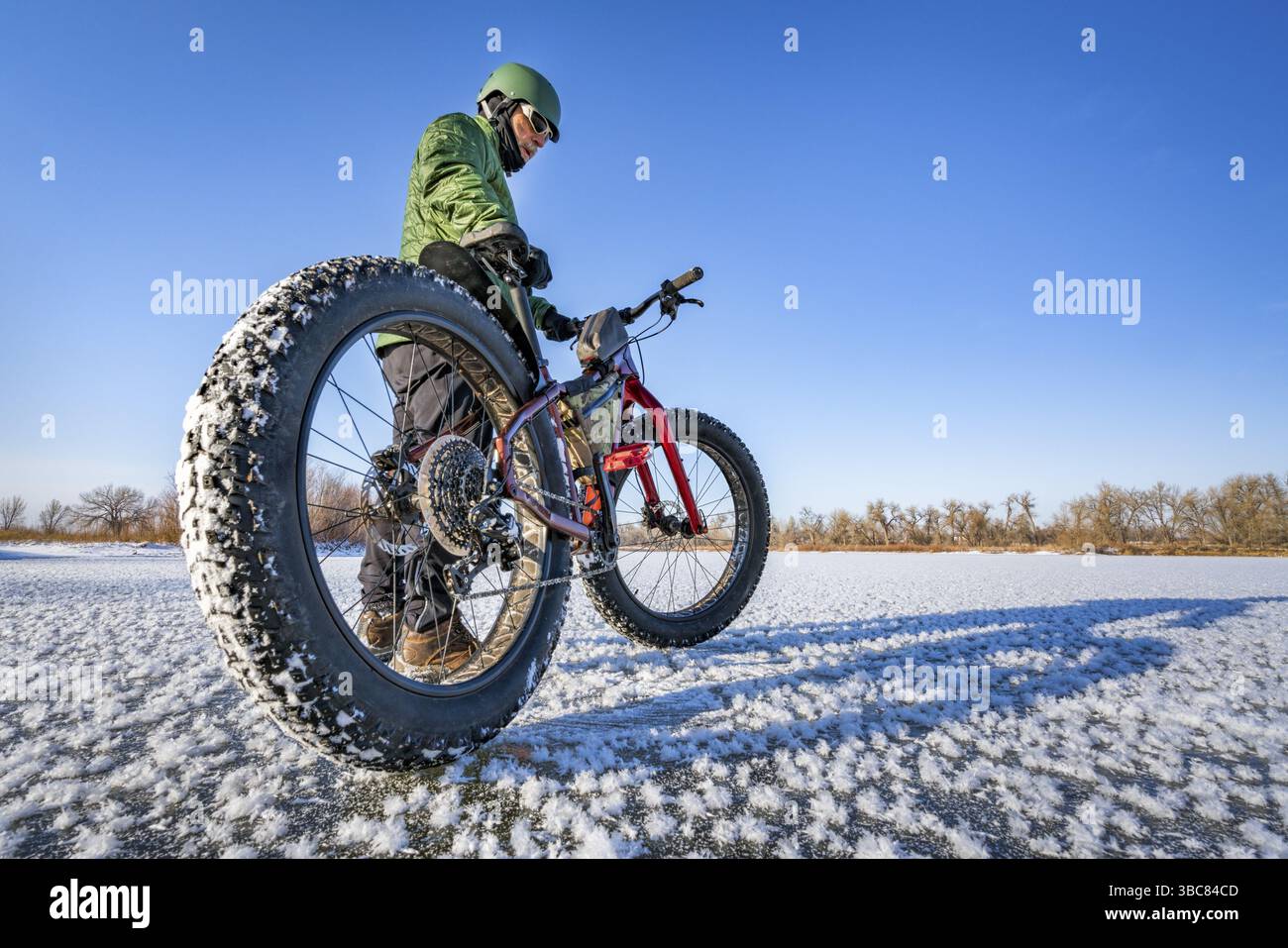 Un cycliste masculin avec son gros vélo de montagne sur un lac gelé dans le nord du Colorado, perspective de lentille grand angle Banque D'Images