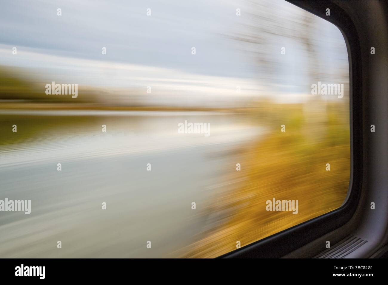 Paysage abstrait flou de lac et de forêt vu d'une fenêtre de train en mouvement Banque D'Images