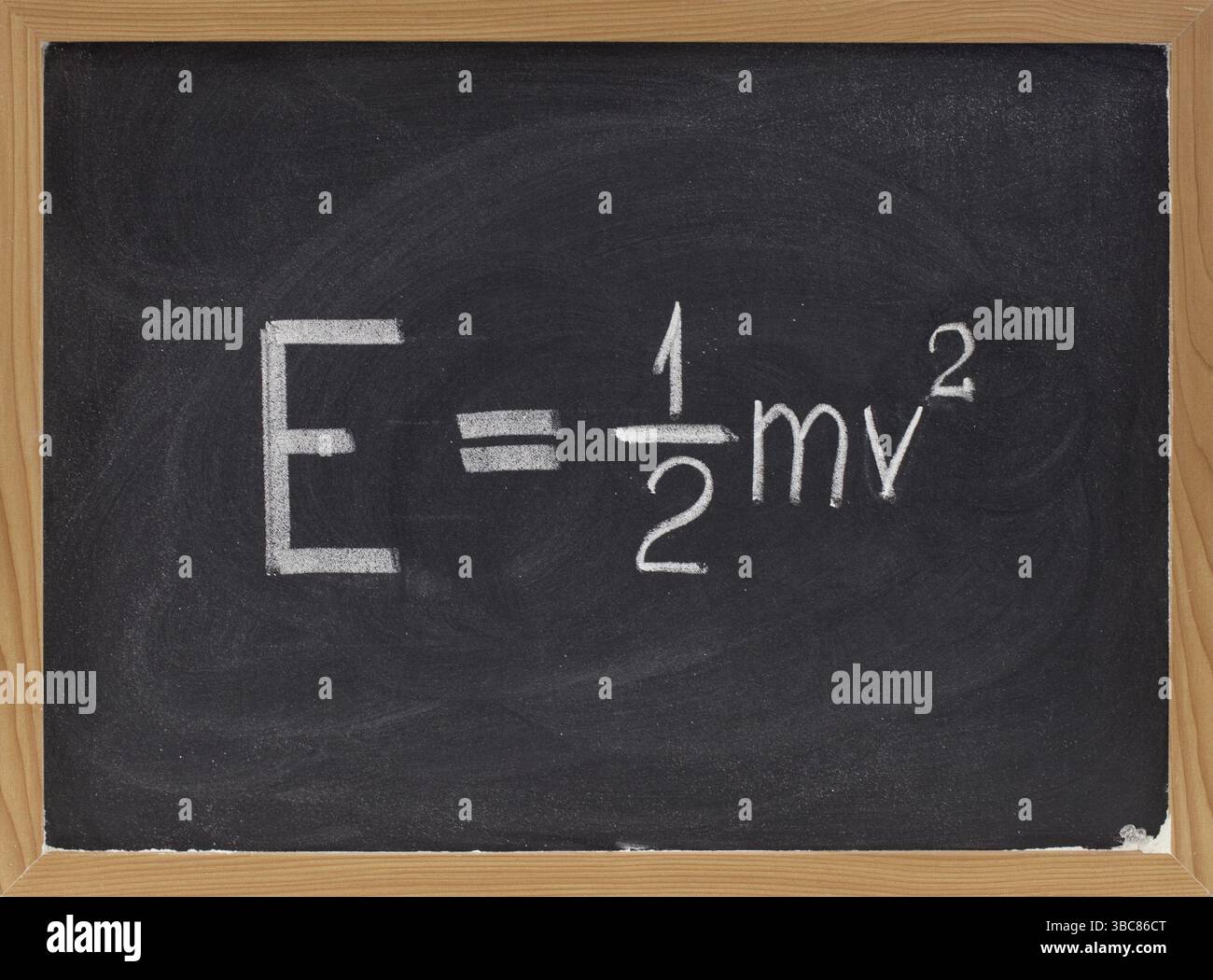 Équation d'énergie cinétique de la mécanique newtonienne classique la reliant à la masse et à la vitesse d'un objet ponctuel - écriture à la craie blanche sur tableau noir Banque D'Images