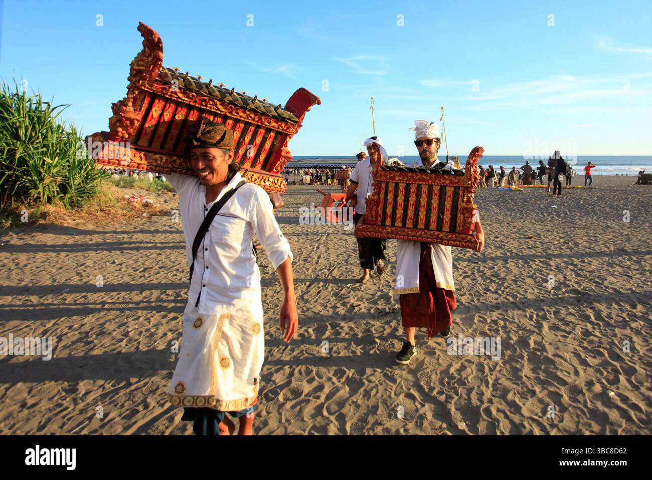 Balinais en vêtements traditionnels qui sont hindous marchent tout en portant des instruments de musique traditionnels après l'événement religieux Melasti. Banque D'Images