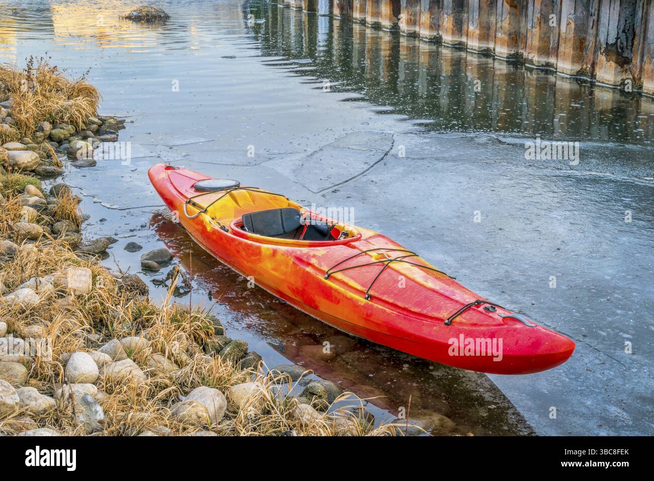 Kayak d'hiver dans le Colorado - kayak d'eau vive rouge sur la rive glacée de St Vrain Creek Banque D'Images