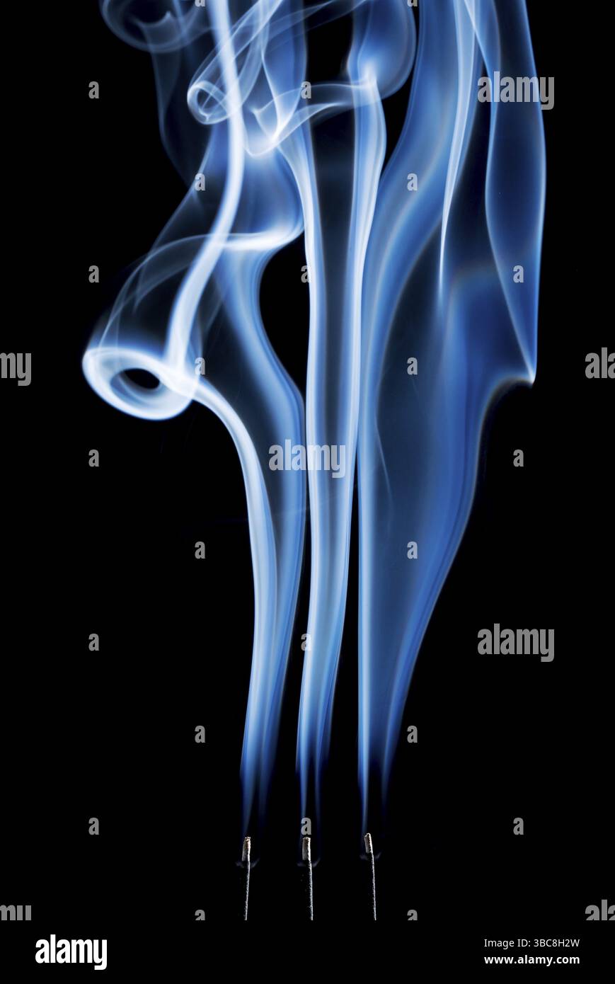 Panaches de fumée délicats, bouffées et tourbillons provenant de la combustion de bâtons d'encens Banque D'Images