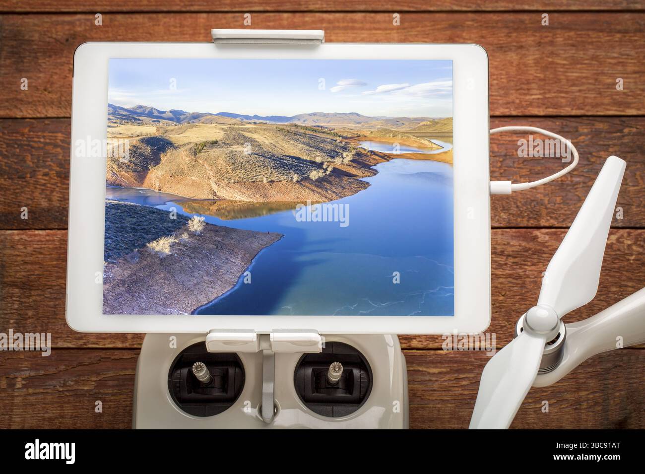 Lac de montagne gelé dans les contreforts du nord du Colorado, examinant une image aérienne sur un balancier numérique monté sur un contrôleur radio de drone Banque D'Images