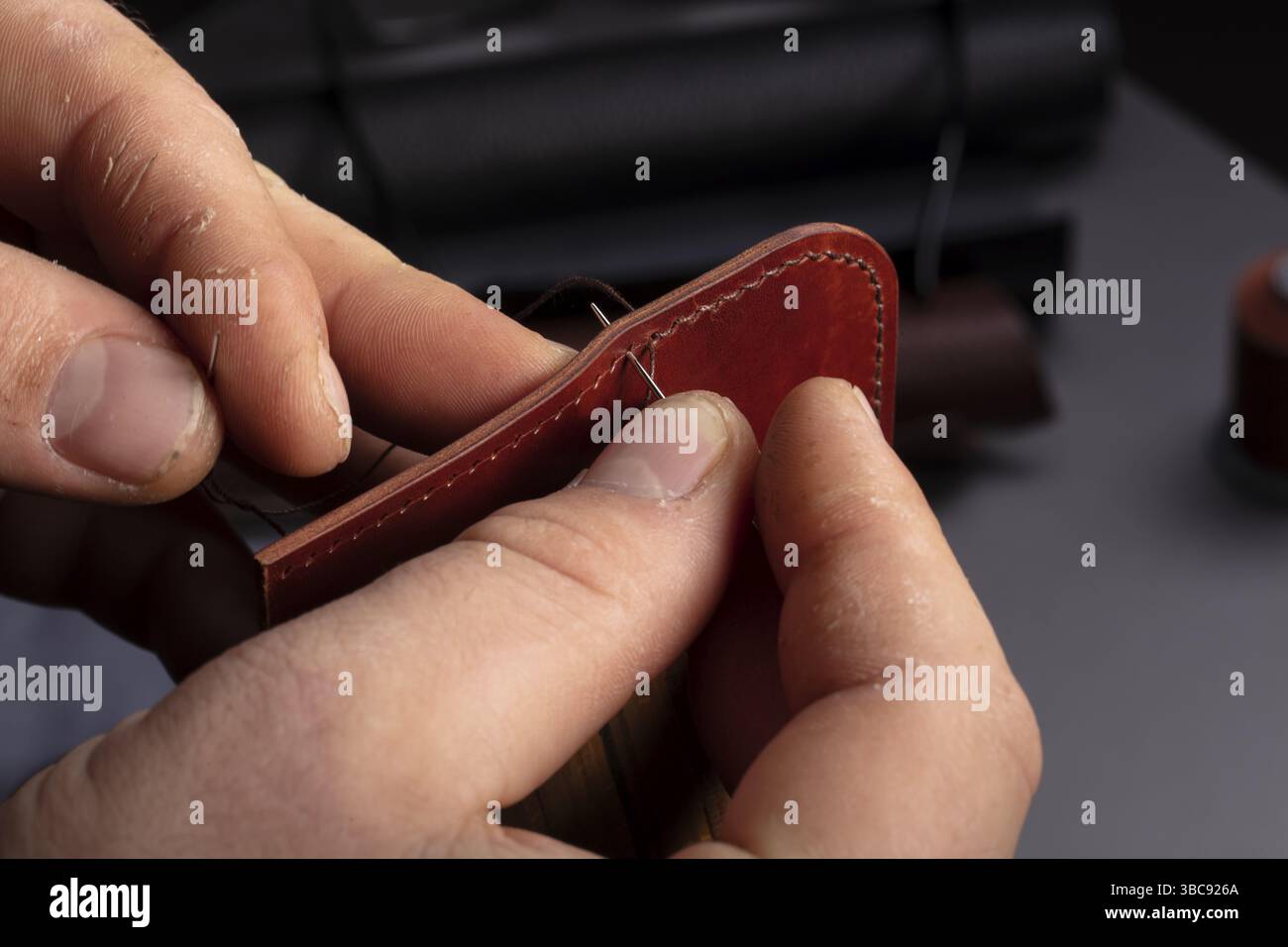 Fabrication de portefeuilles en cuir. Les mains du maître cousent un produit en cuir Banque D'Images