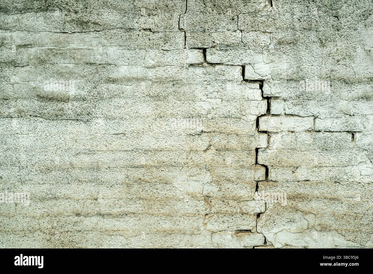 Ancienne structure de mur de briques blanches fissurée endommagée, en raison de la défaillance de la fondation structurelle et de la détérioration des matériaux de construction, comme arrière-plan urbain Banque D'Images