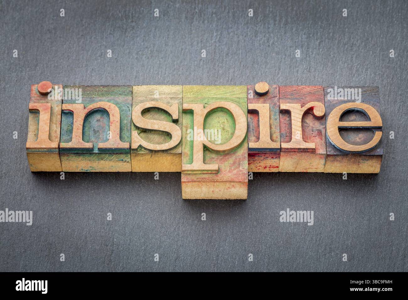Inspirez le mot dans les blocs d'impression typographiques en bois teints par des encres de couleur sur fond de roche ardoise Banque D'Images