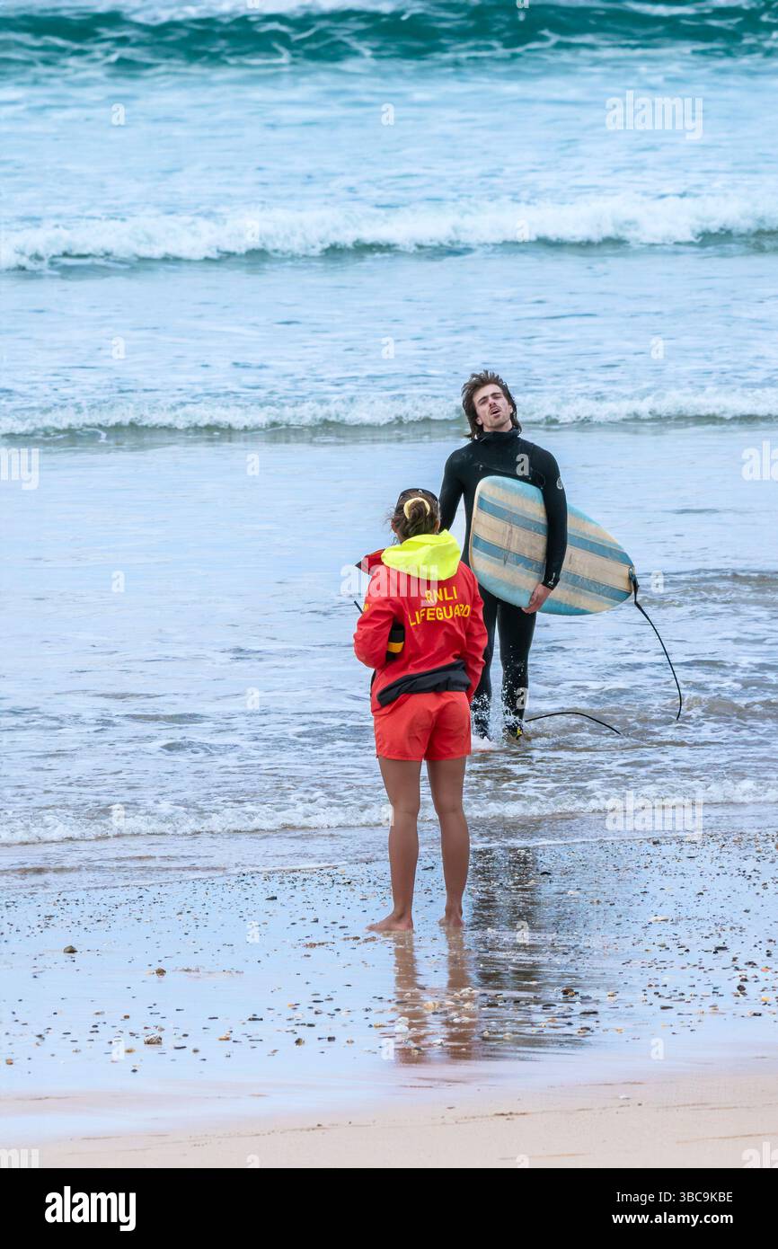Une sauveteuse RNLI donnant des conseils de sécurité aux surfeurs sur la plage de Fistral à Newquay en Cornouailles au Royaume-Uni. Banque D'Images Une sauveteuse RNLI donnant des conseils de sécurité aux surfeurs sur la plage de Fistral à Newquay en Cornouailles au Royaume-Uni. Banque D'Images