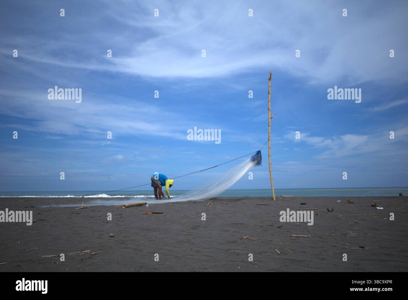 Un pêcheur prépare un filet pour pêcher du poisson à Congot Beach, Kulon Progo, Yogyakarta, Indonésie. Banque D'Images