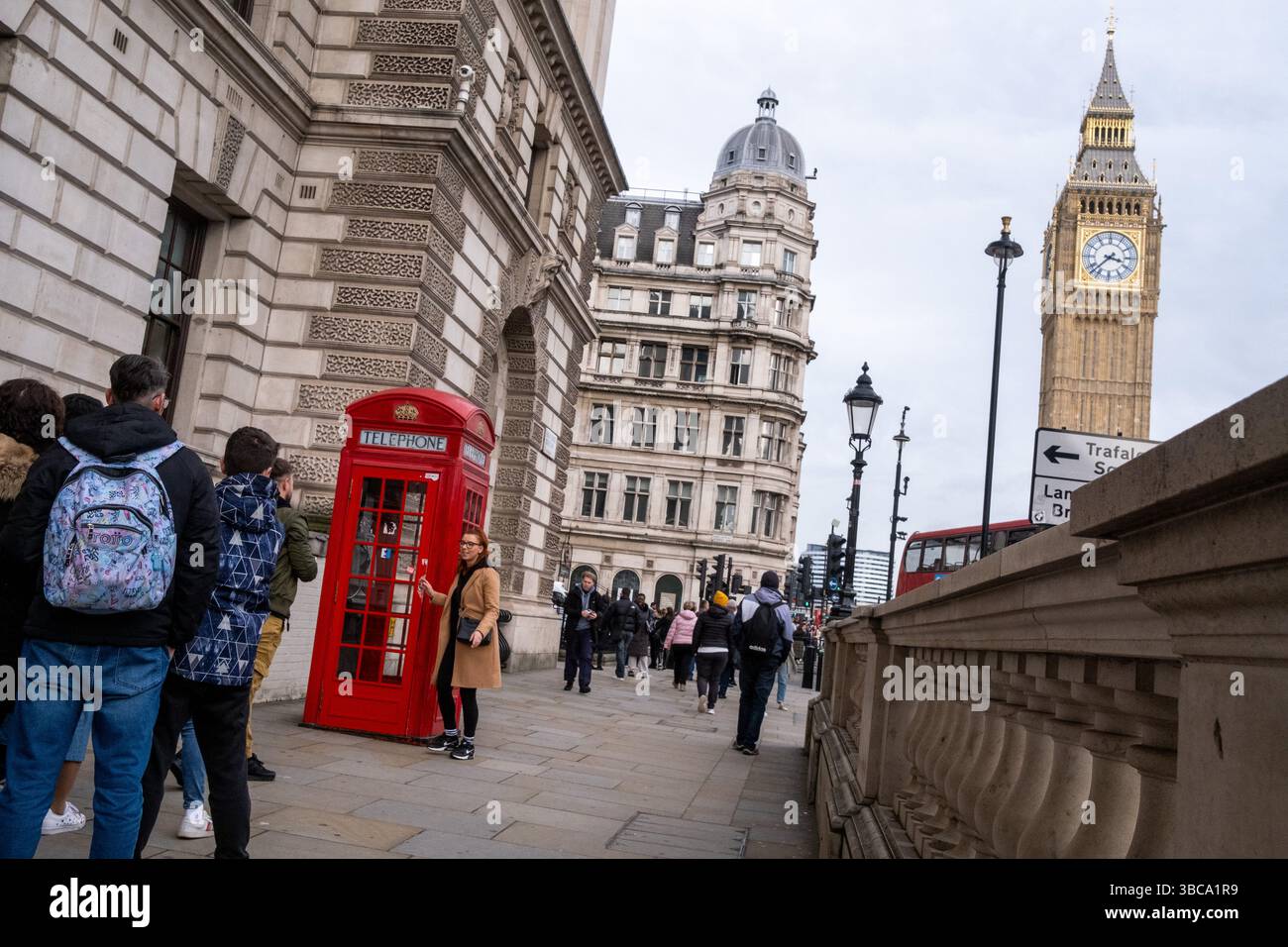 Touriste prenant une photo avec son smartphone avec une cabine téléphonique rouge emblématique à la périphérie du Palais de Westminster avec Big Ben dans la ville Banque D'Images