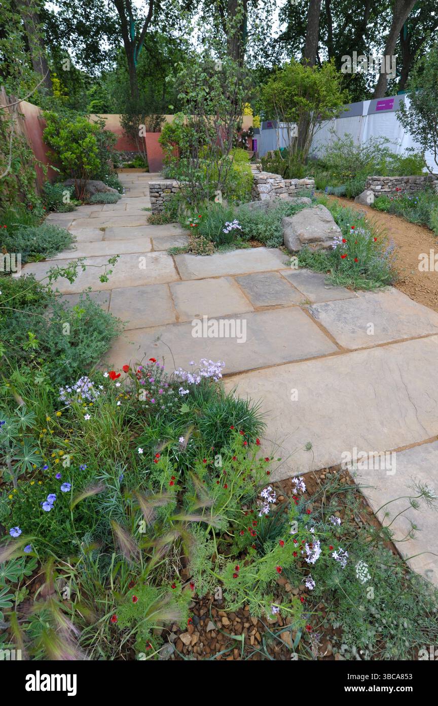 Londres, Royaume-Uni. 19 mai 2025. Journée d'ouverture au salon des fleurs de Chelsea de la Royal Horticultural Society 2025 - l'un des jardins d'exposition exposés : The Hospice UK : Garden of compassion Garden. Inspiré par les paysages du comté de Durham et de la Méditerranée, ce jardin résistant au climat présente des murs rendus, des rochers et un banc incurvé faisant écho à l'usure de la rivière. Conçu pour Hospice UK, il offre des chemins entièrement accessibles pour tous les utilisateurs, y compris les patients dans les lits, et offre des espaces variés de repos, de réflexion et de connexion avec la nature. Crédit : Michael Preston/Alamy Live News Banque D'Images