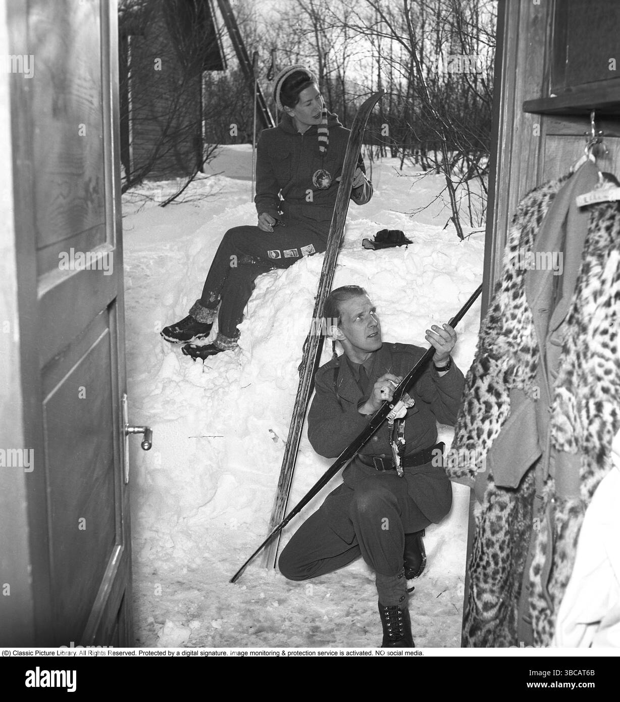 Hiver dans les années 1940 Un jeune couple va skier et prépare les skis avec de la cire de ski pour obtenir une meilleure traction sur la neige. C'est le couple marié Iris et Bertil Thorelli qui a loué une cabane à Björkliden, loin au nord de la laponie suédoise. Suède 1943 photo Kristoffersson ref D109-1 Banque D'Images