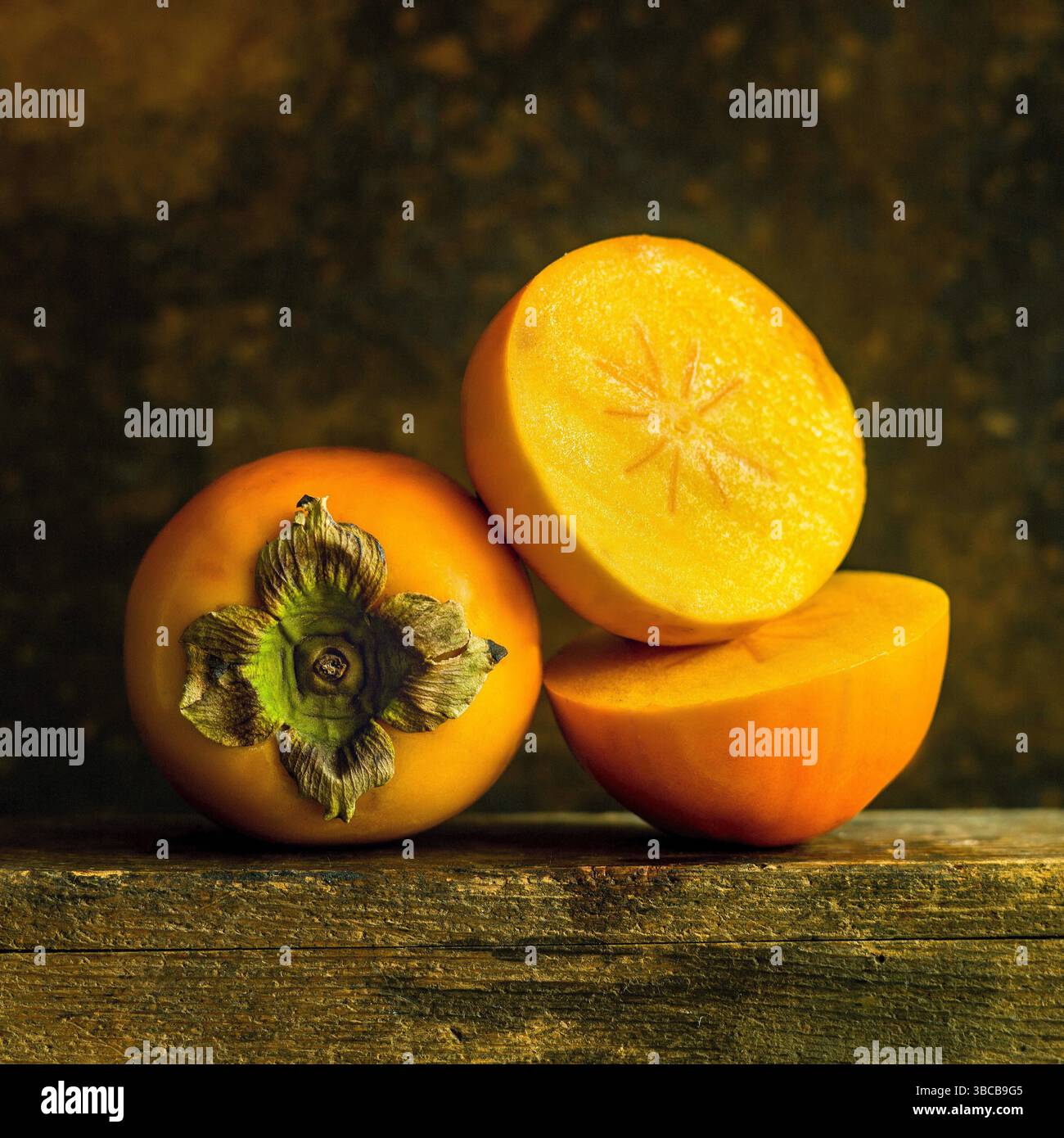 Les kakis mûrs sont disposés soigneusement, affichant leur peau lisse et leur chair orange vif. Banque D'Images
