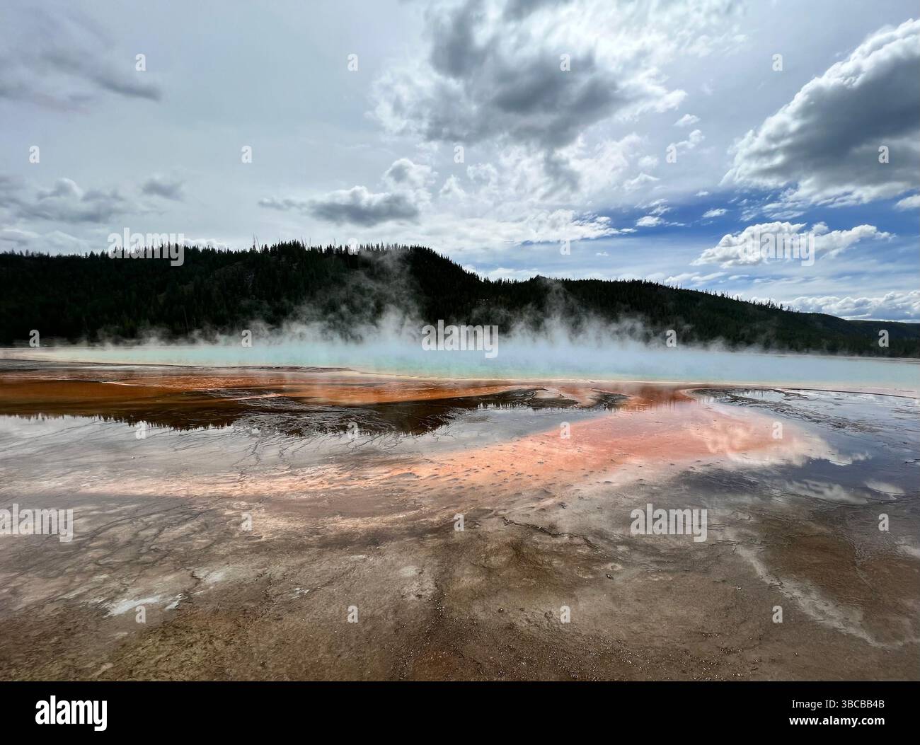L'équipe dérive à travers la surface minérale vive de Grand Prismatic Spring dans le parc national de Yellowstone, avec des reflets colorés reflétés dans le peu profond. Banque D'Images