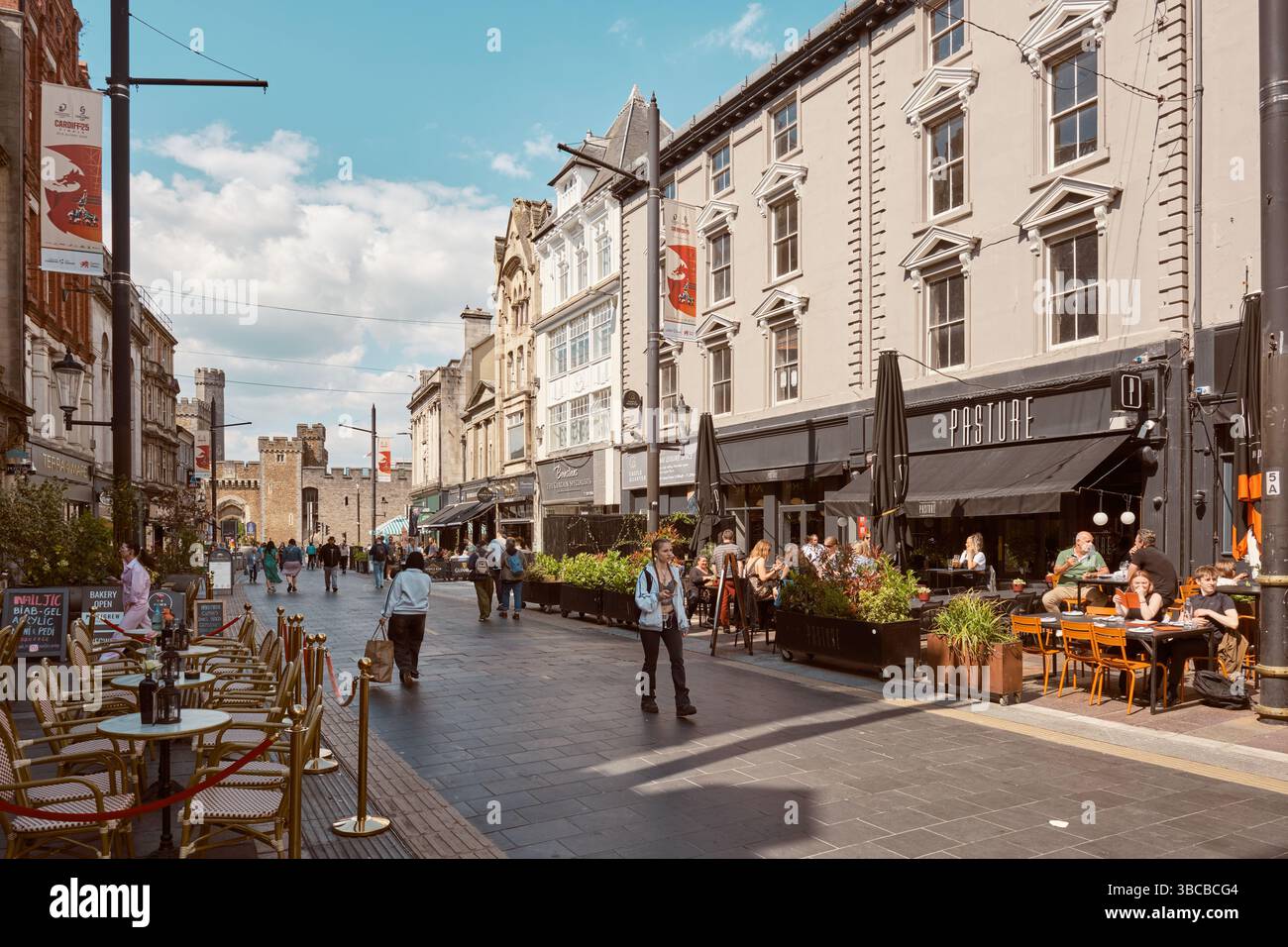 Cardiff, South Glamorgan, pays de Galles, Europe - 09 mai 2025 : dîner en plein air sur St Mary's Street par une journée ensoleillée avec le château en arrière-plan. Banque D'Images