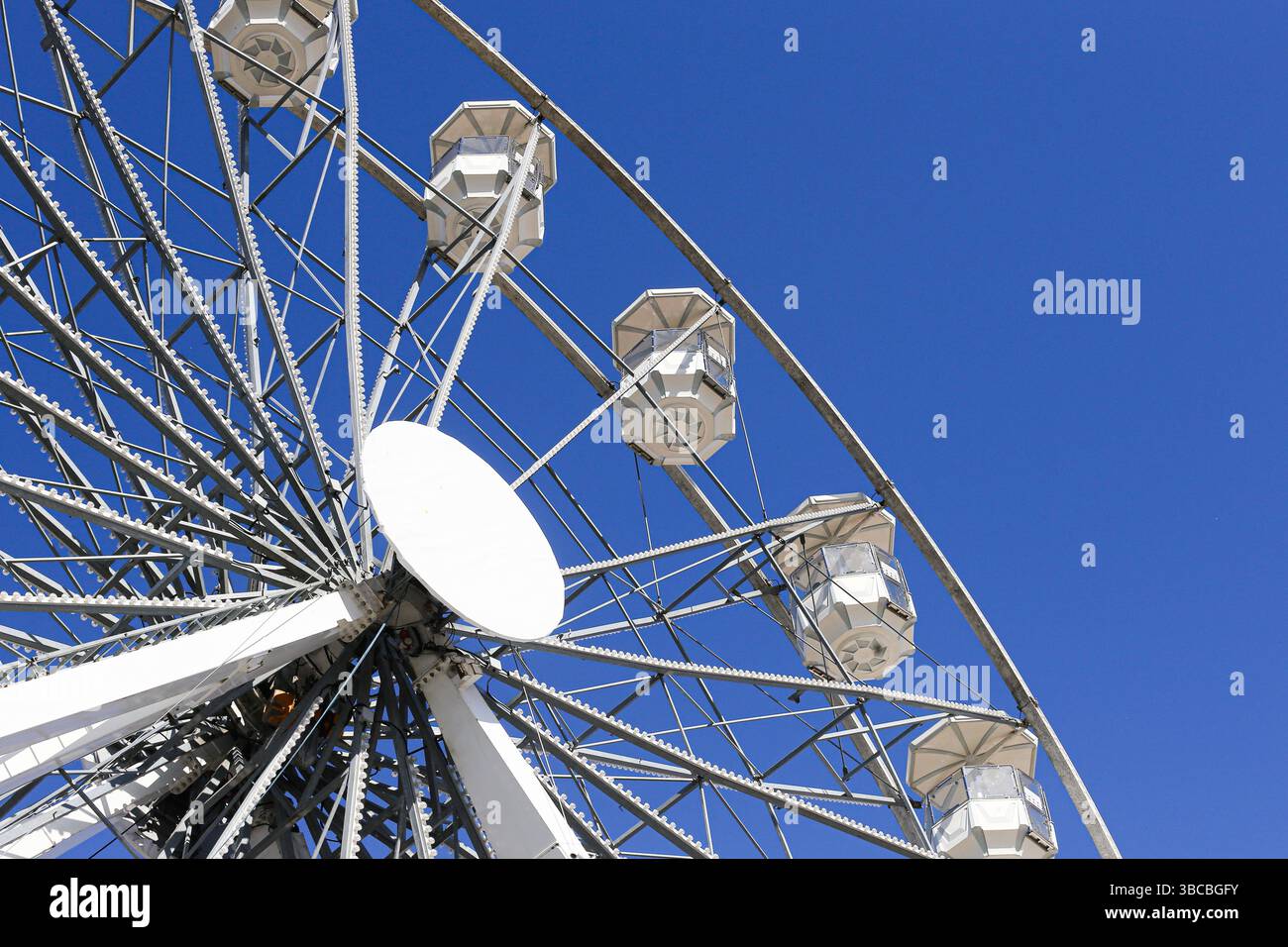 Attraction de la grande roue blanche. Manège rotatif géant. Fond bleu de ciel d'été. Fête foraine de carnaval. Structure métallique ronde. Banque D'Images