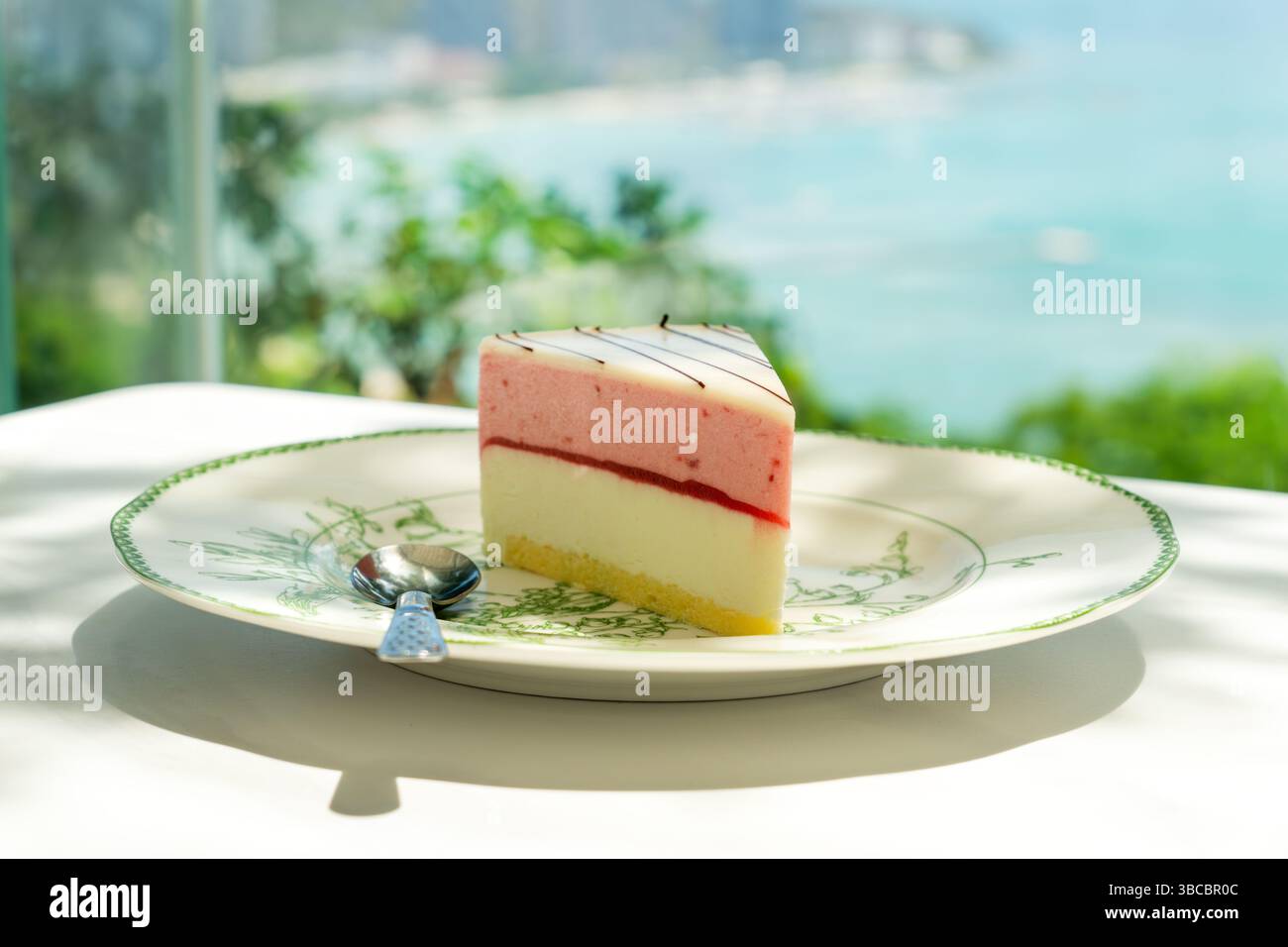 Crêpes aux fraises au-dessus de la mer. morceau de gâteau rose et blanc sur la table dans le restaurant sur fond de mer Banque D'Images