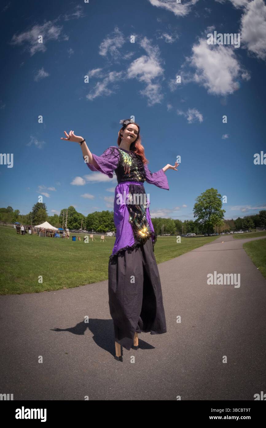 Une jeune dame sur pilotis étend ses mains étendues sous un ciel rempli de nuages. Au Pirate Festival de New Paltz, New York. Banque D'Images
