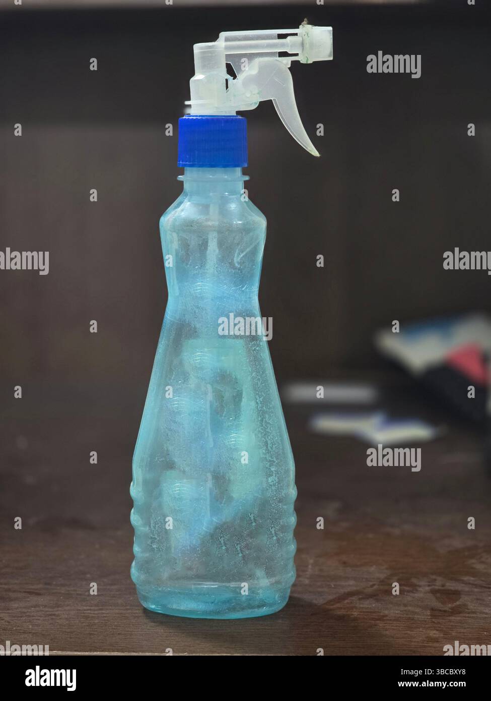 Vaporisateur en plastique bleu clair sur bois foncé - Image de stock capturée avec un smartphone