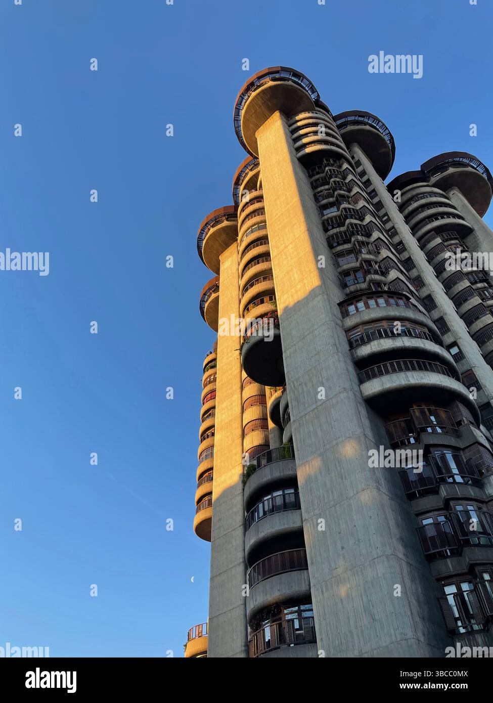 Vue architecturale unique d'une tour résidentielle de Madrid, avec des courbes audacieuses et un design moderniste sous la lumière chaude de l'après-midi. Banque D'Images