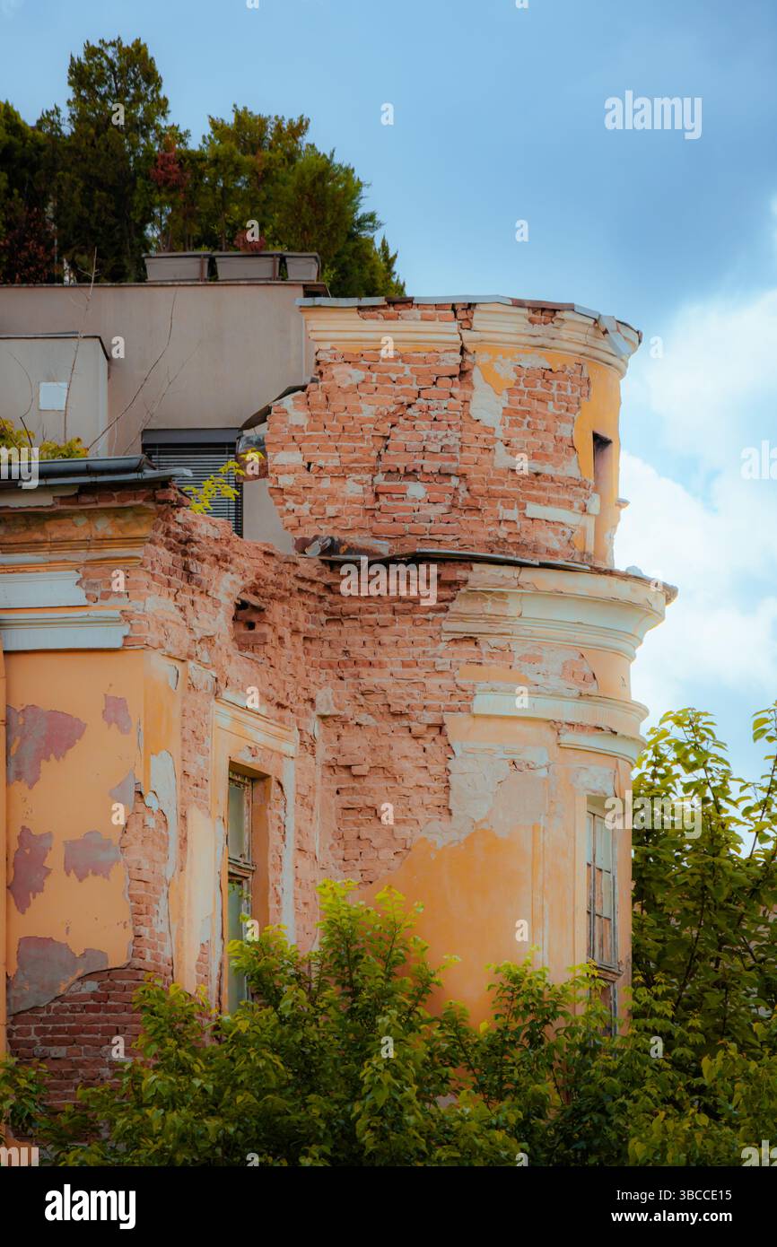 Un vieux bâtiment avec un extérieur orange écaillé montre des dommages importants car les briques sont exposées. Banque D'Images