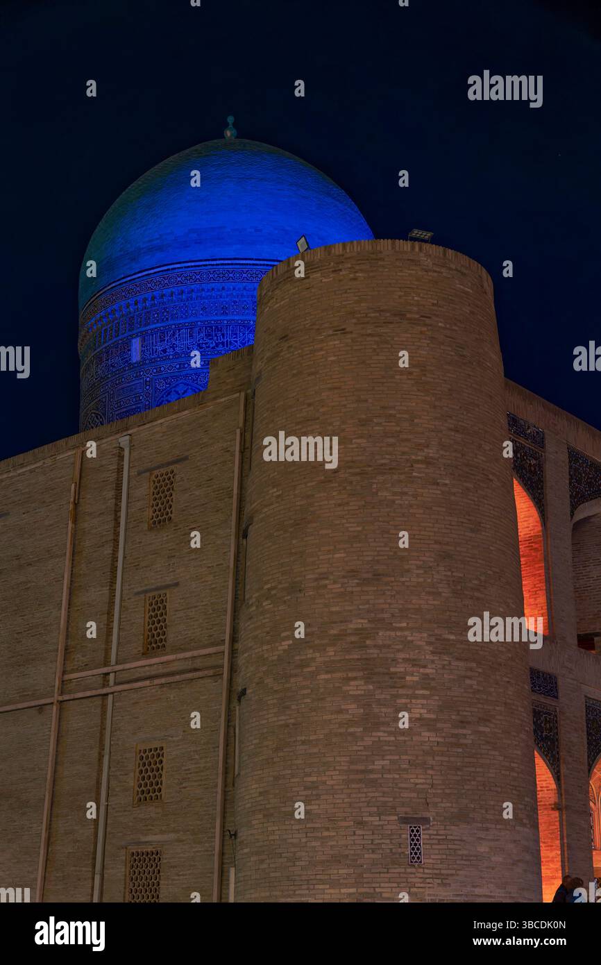 Un dôme bleu de la Madrasah Mir-i-Arab à Boukhara, en Ouzbékistan, est illuminé la nuit, symbolisant l’éducation islamique durable de la ville. Banque D'Images