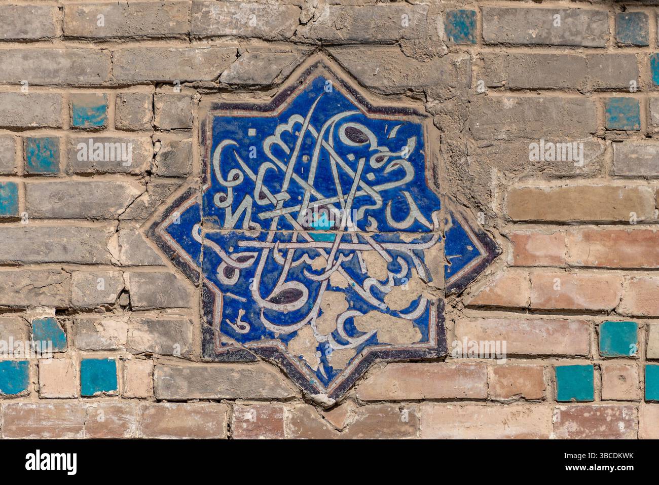 Une tuile émaillée bleue avec une calligraphie complexe décore le mur de briques de la Madrasah Ulugbek à Boukhara, en Ouzbékistan, reflétant le patrimoine artistique islamique. Banque D'Images