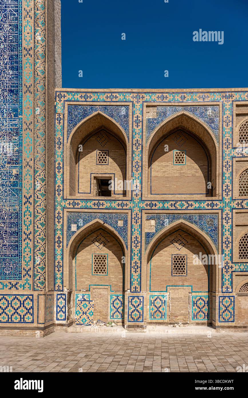 Une façade avec des arcs pointus et des bandes de tuiles bleues marque la Madrasah Ulugbek à Boukhara, Ouzbékistan, un centre d'apprentissage et de culture Timuride. Banque D'Images