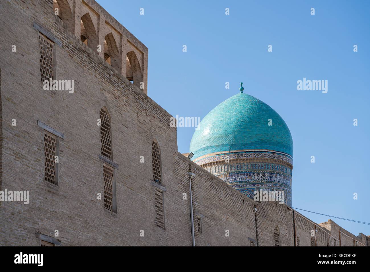 Une longue façade en brique avec des fenêtres cintrées ligne Mir-i-Arab Madrasa à Boukhara, Ouzbékistan, montrant l'échelle de cette institution historique. Banque D'Images