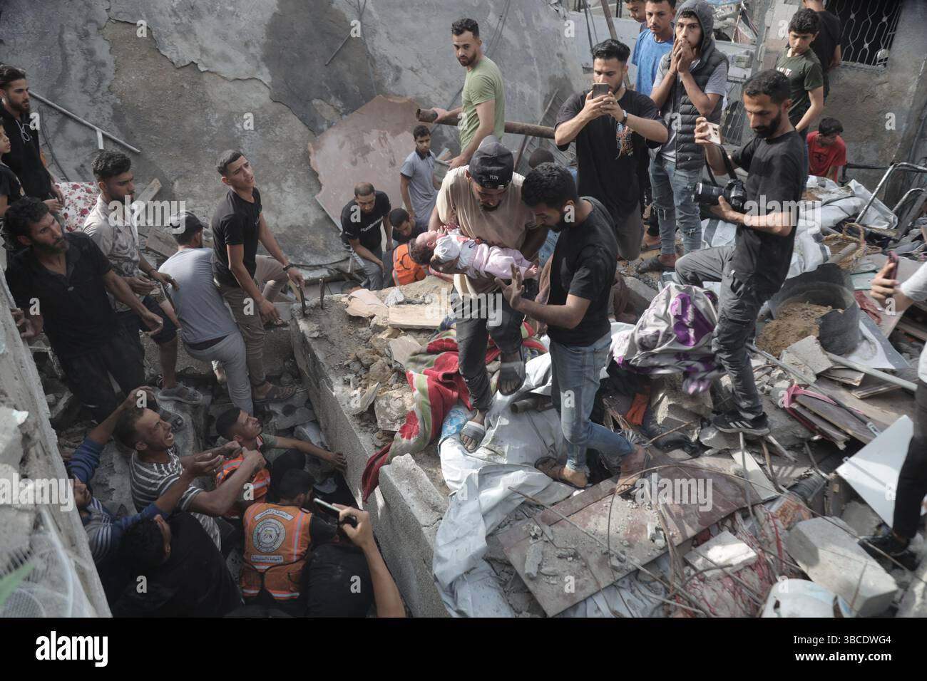 Pékin, Chine. 18 mai 2025. Des gens transfèrent un bébé après une frappe aérienne israélienne dans le camp de réfugiés de Jabalia dans le Nord de la bande de Gaza, le 18 mai 2025. Le nombre de morts parmi les Palestiniens suite aux attaques israéliennes dans la bande de Gaza depuis l’aube de dimanche est passé à 140, selon la Défense civile à Gaza. Crédit : Abdul Rahman Salama/Xinhua/Alamy Live News Banque D'Images