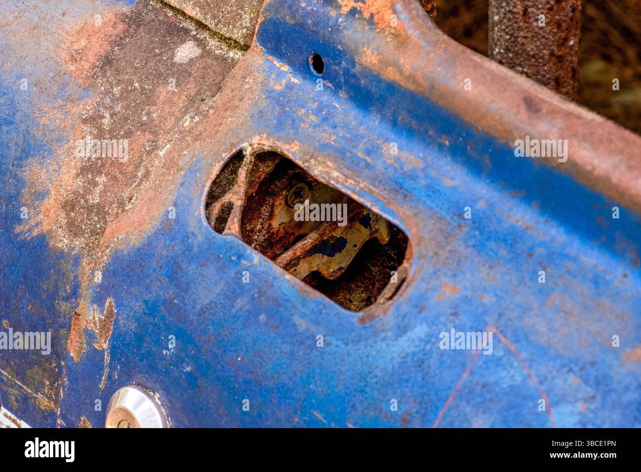 Gros plan d'une porte de voiture de course bleue rouillée avec peinture écaillée et mécanisme de verrouillage intérieur exposé, mettant en évidence la décomposition et l'abandon vintage. Banque D'Images