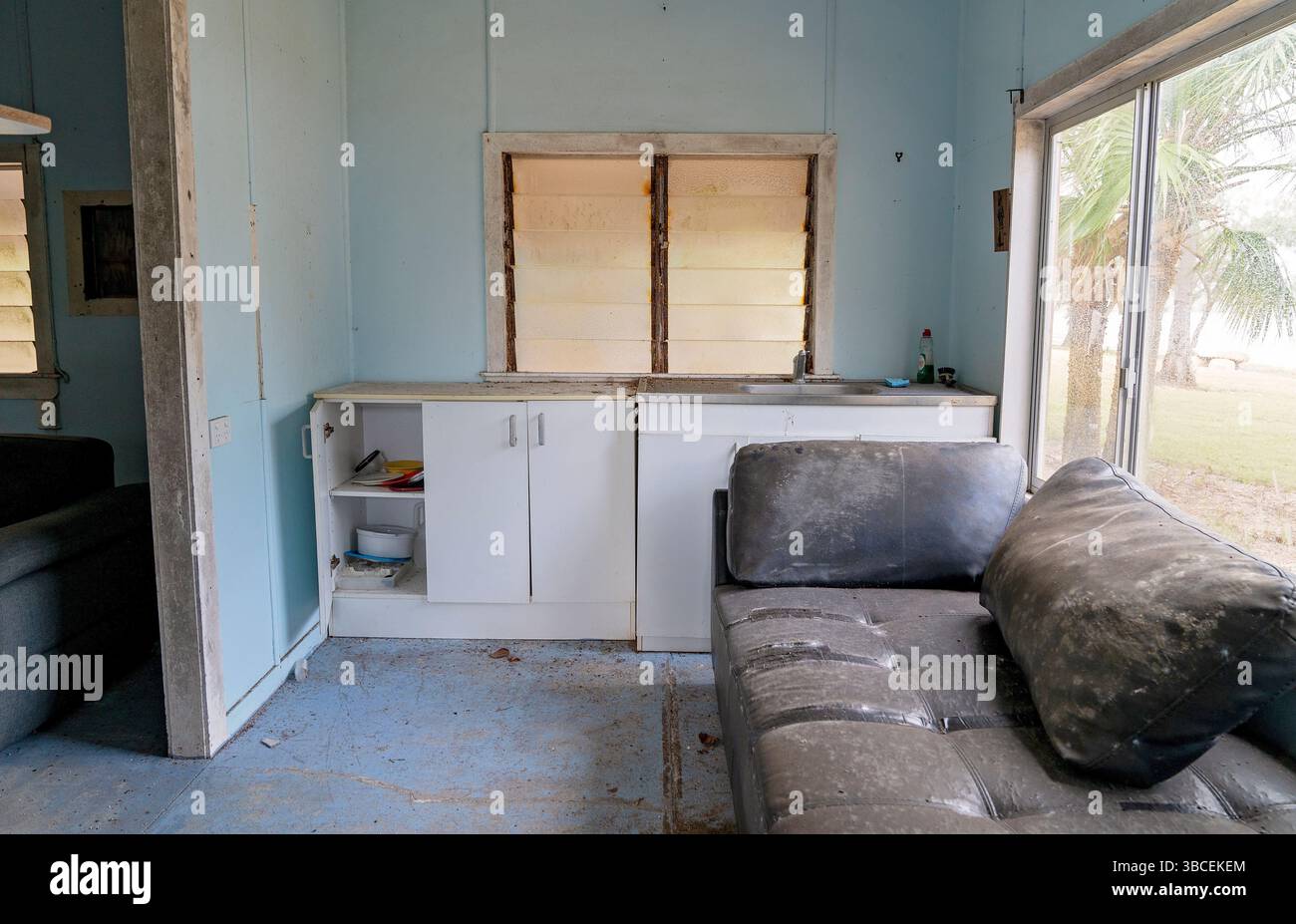 une kitchenette de base et des sols sablonneux montrant des signes de long abandon. Banque D'Images