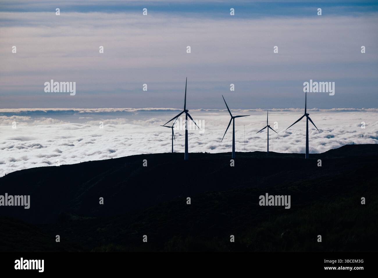 Les éoliennes silhouettes se dressent hautes sur une crête de montagne au-dessus d'une mer de nuages Banque D'Images