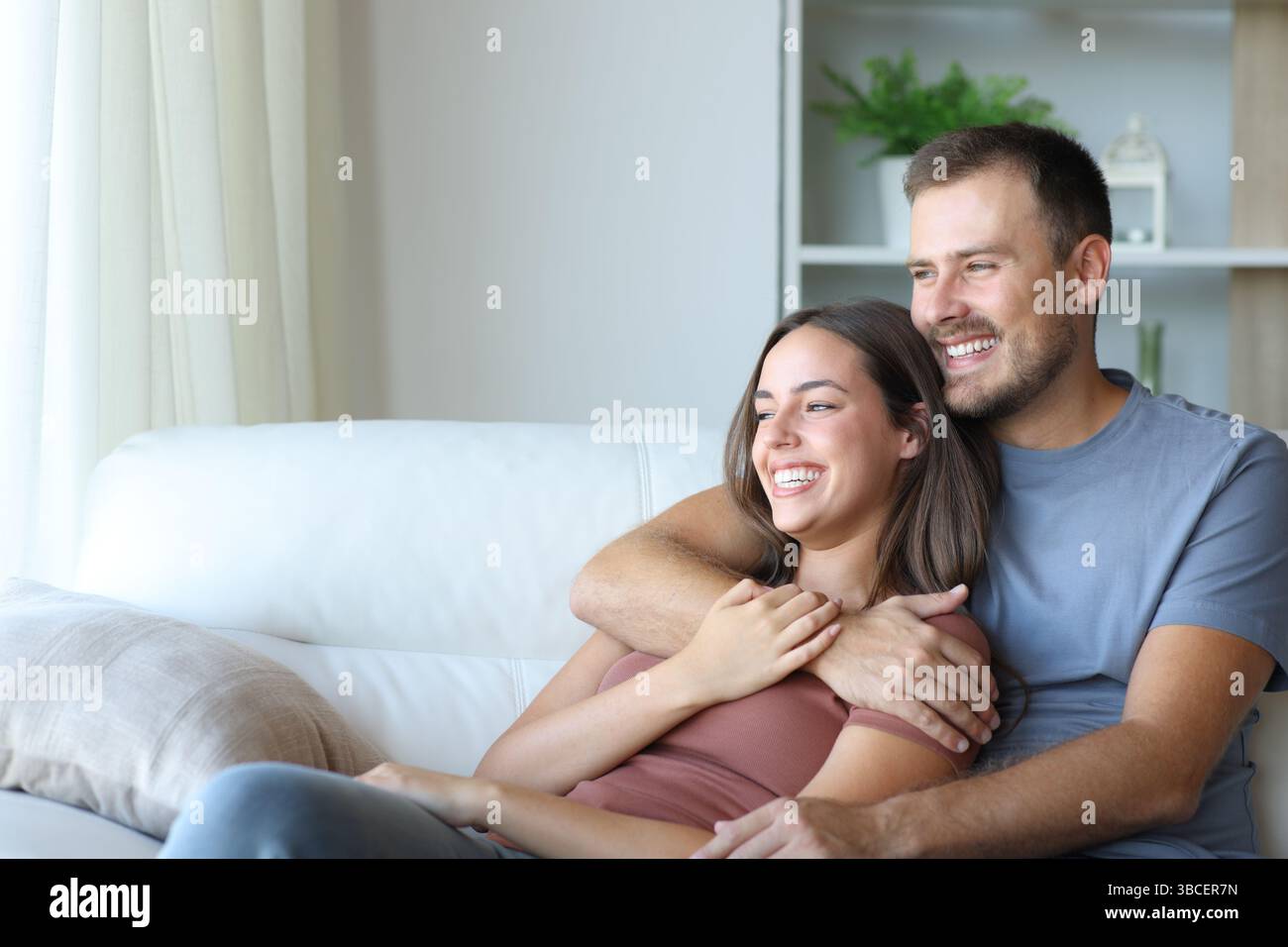 Couple heureux embrassant et se relaxant assis sur un canapé à la maison Banque D'Images