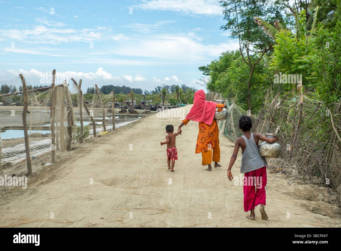Les Bangladais transportent de l'eau potable après l'avoir recueillie d'une source d'eau douce dans la zone côtière de Banshkhali, Chittagong Banque D'Images