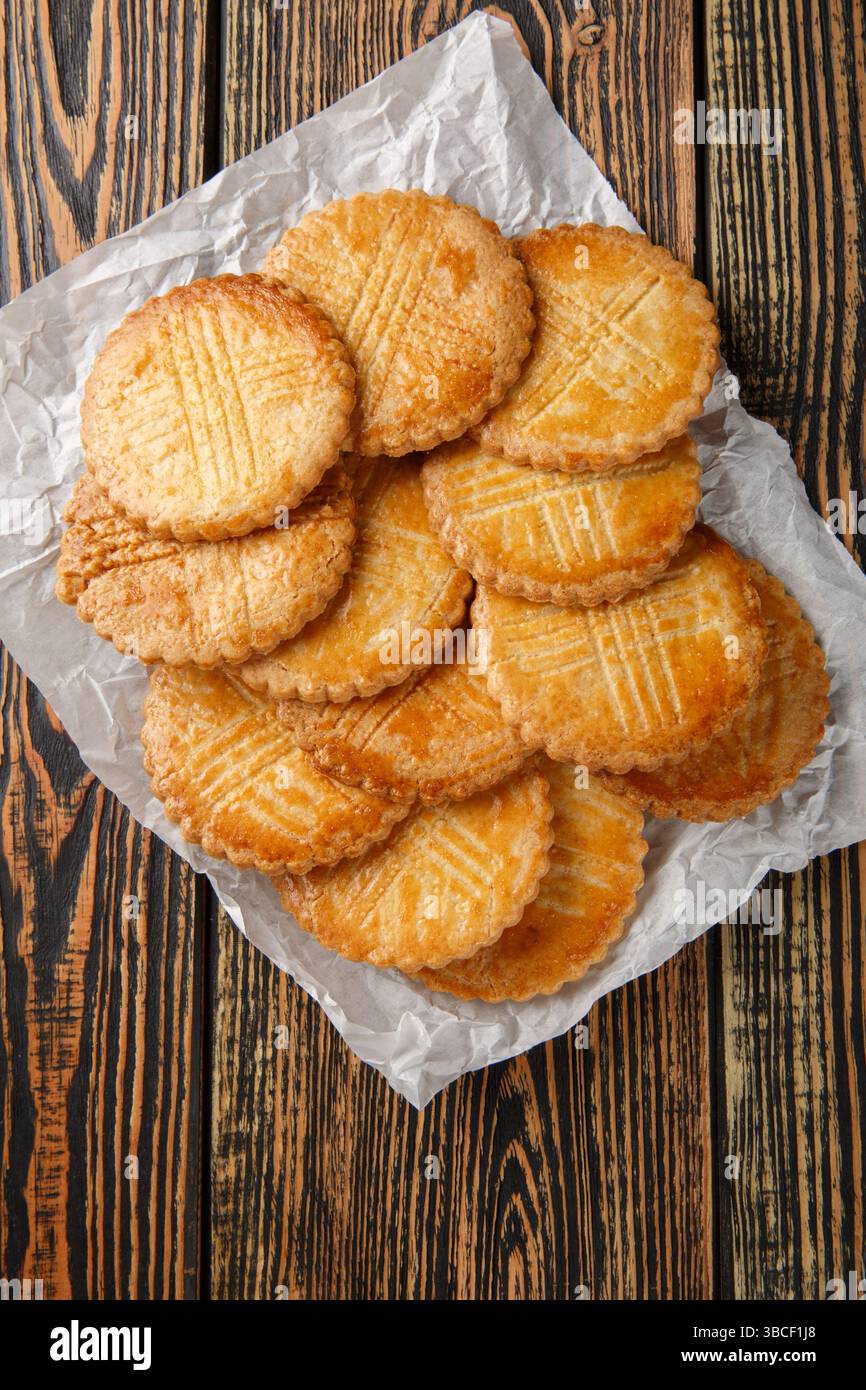 Sable Breton est un biscuit classique, très beurré provenant de la région Bretagne gros plan sur papier parchemin sur table en bois. Vue de dessus verticale de ci-dessus Banque D'Images