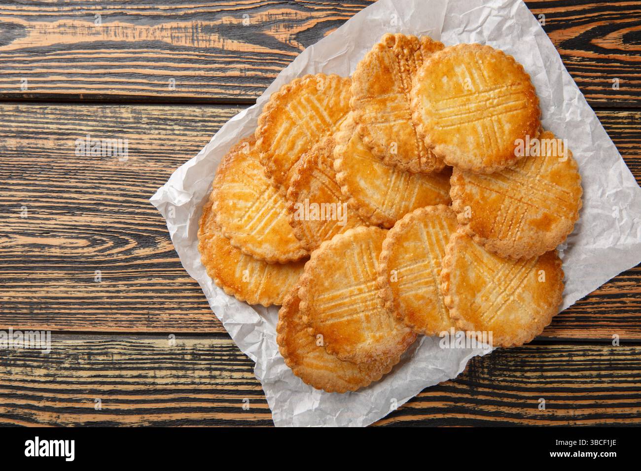 Sable Breton biscuits sablés sucrés-salés gros plan sur papier parchemin sur table en bois. Vue horizontale de dessus Banque D'Images