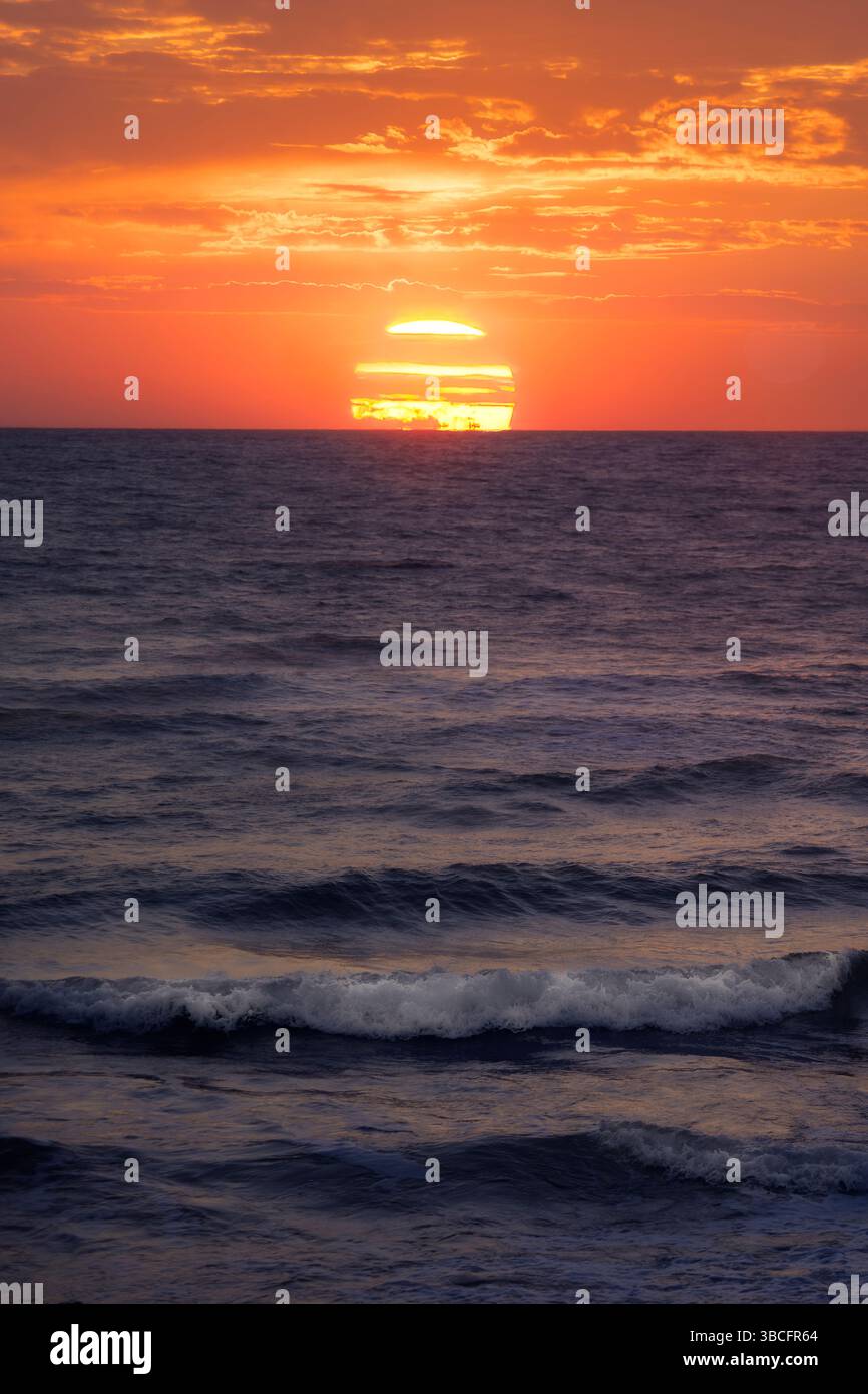 La lumière dorée du soleil se reflète sur la surface de l'océan, créant un moment serein au crépuscule, invitant à la paix et à la contemplation. Banque D'Images