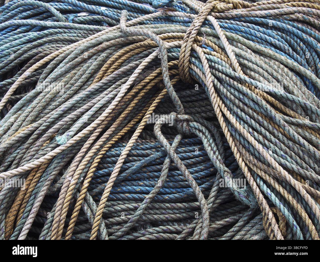 Pile de vieille corde de pêche marine enroulée et nouée bleue dans les tons de bleu et de brun Banque D'Images