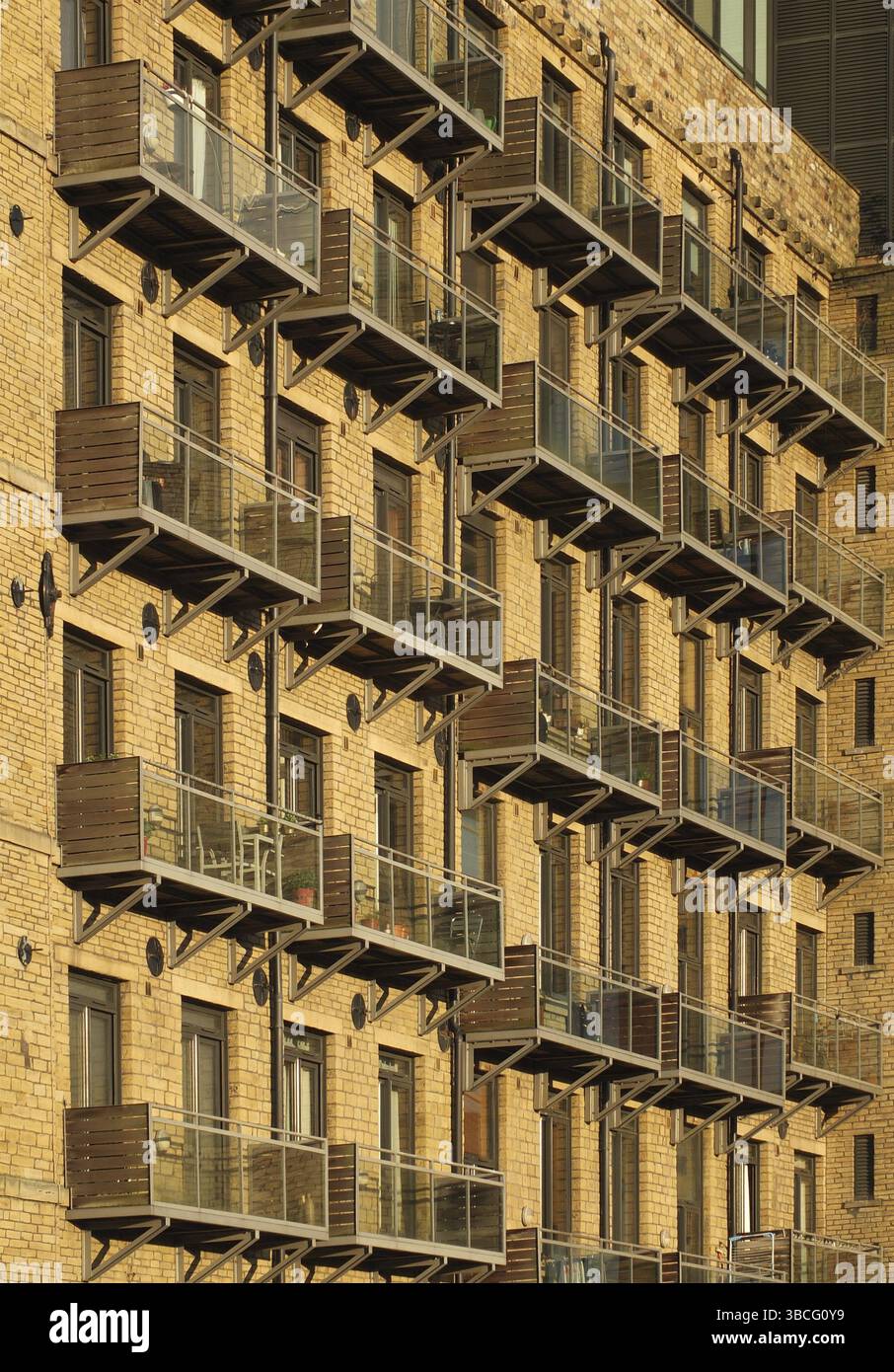 Vue en perspective sur la façade d'un grand ancien moulin en pierre transformé en appartements avec balcons modernes en verre Banque D'Images