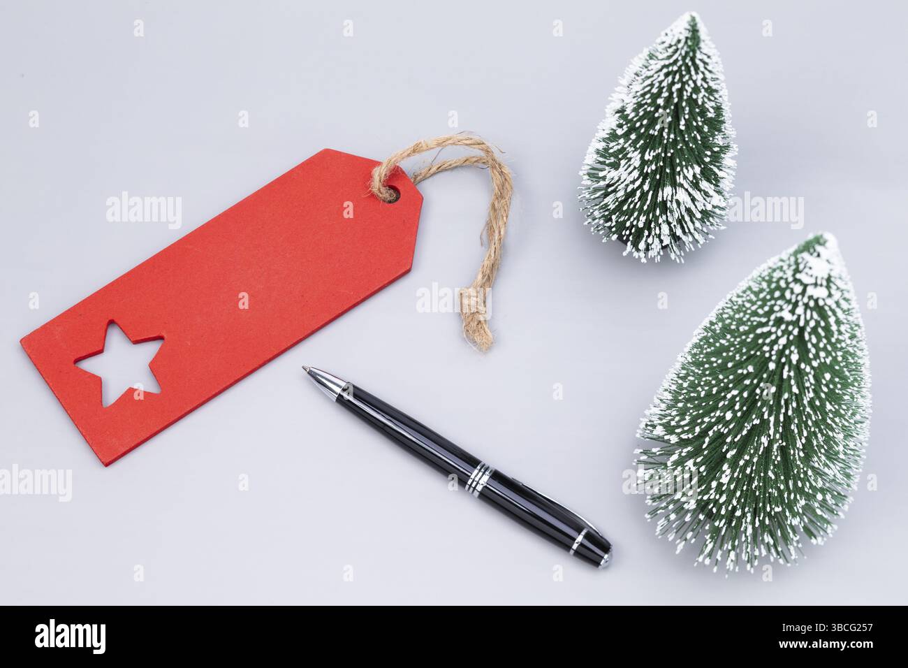 La photo montre une étiquette rouge avec deux arbres de Noël artificiels recouverts de neige et une lettre de boule Banque D'Images