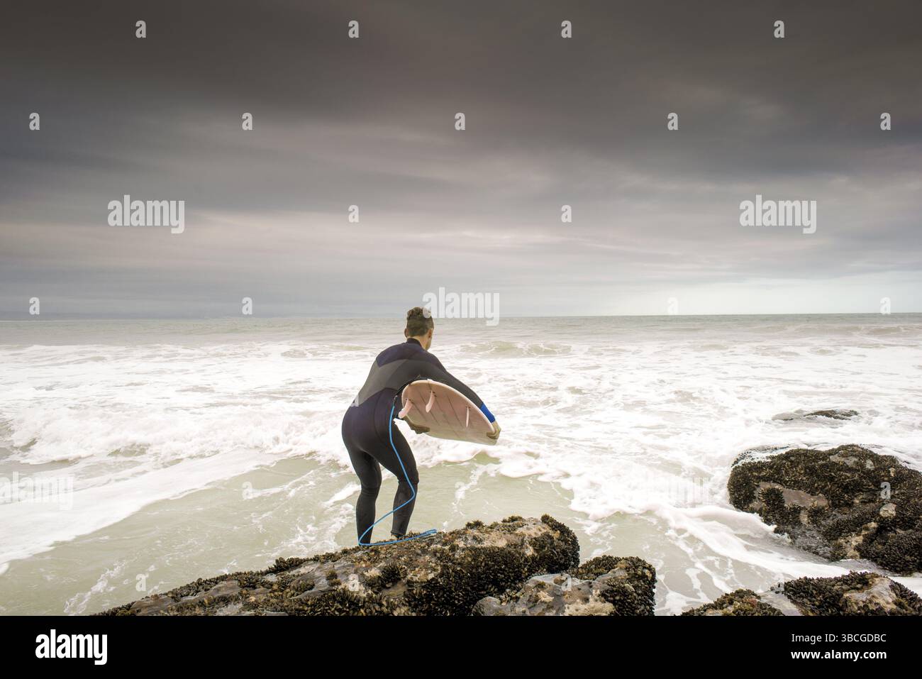 Un surfeur saute dans l'océan avec sa planche de surf sous le bras à Jeffrey's Bay, Afrique du Sud, Afrique Banque D'Images