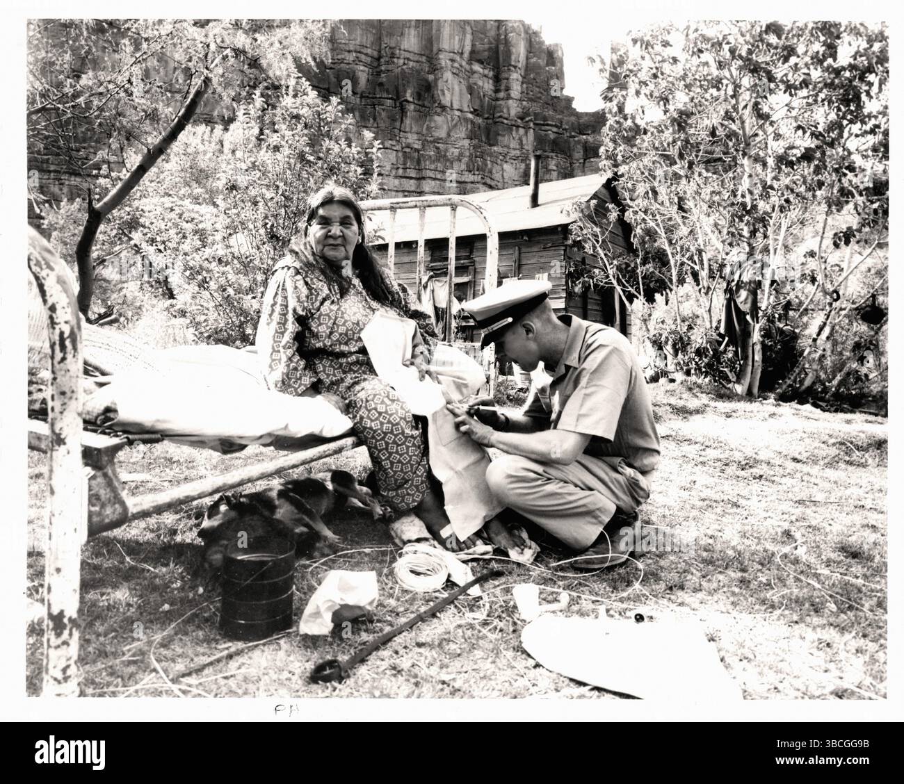 Havasupai femme indienne assise sur un lit reçoit une injection dans son genou d'un officier PHS - document historique, photographe inconnu Banque D'Images