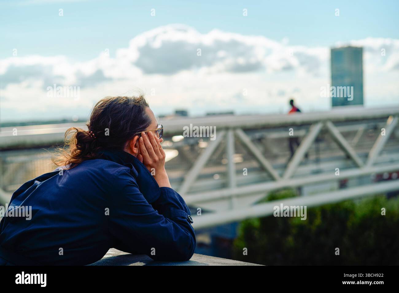 Personne en veste bleue regardant au-dessus du paysage urbain avec des nuages et un gratte-ciel lointain. Bruxelles, Belgique Banque D'Images