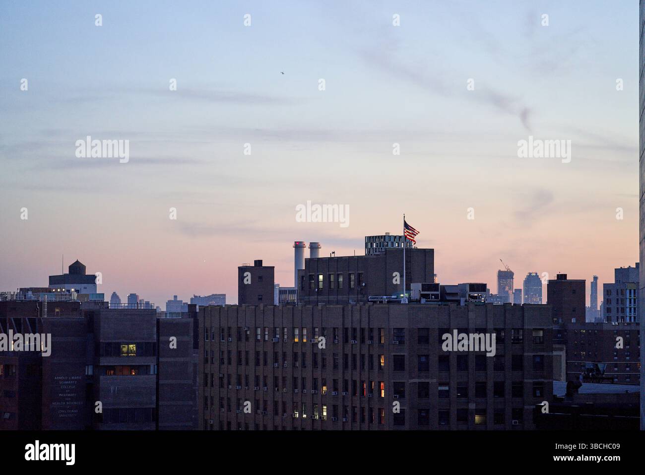 Horizon de la ville au crépuscule avec des bâtiments et un drapeau américain sur le toit. New York, États-Unis Banque D'Images
