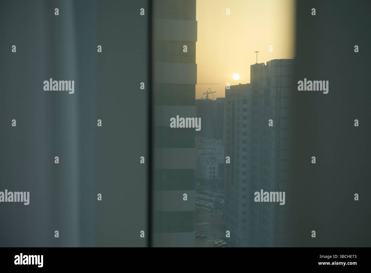 Paysage urbain avec des gratte-ciel et un coucher de soleil brumeux vu par une fenêtre. Abu Dhabi, eau Banque D'Images