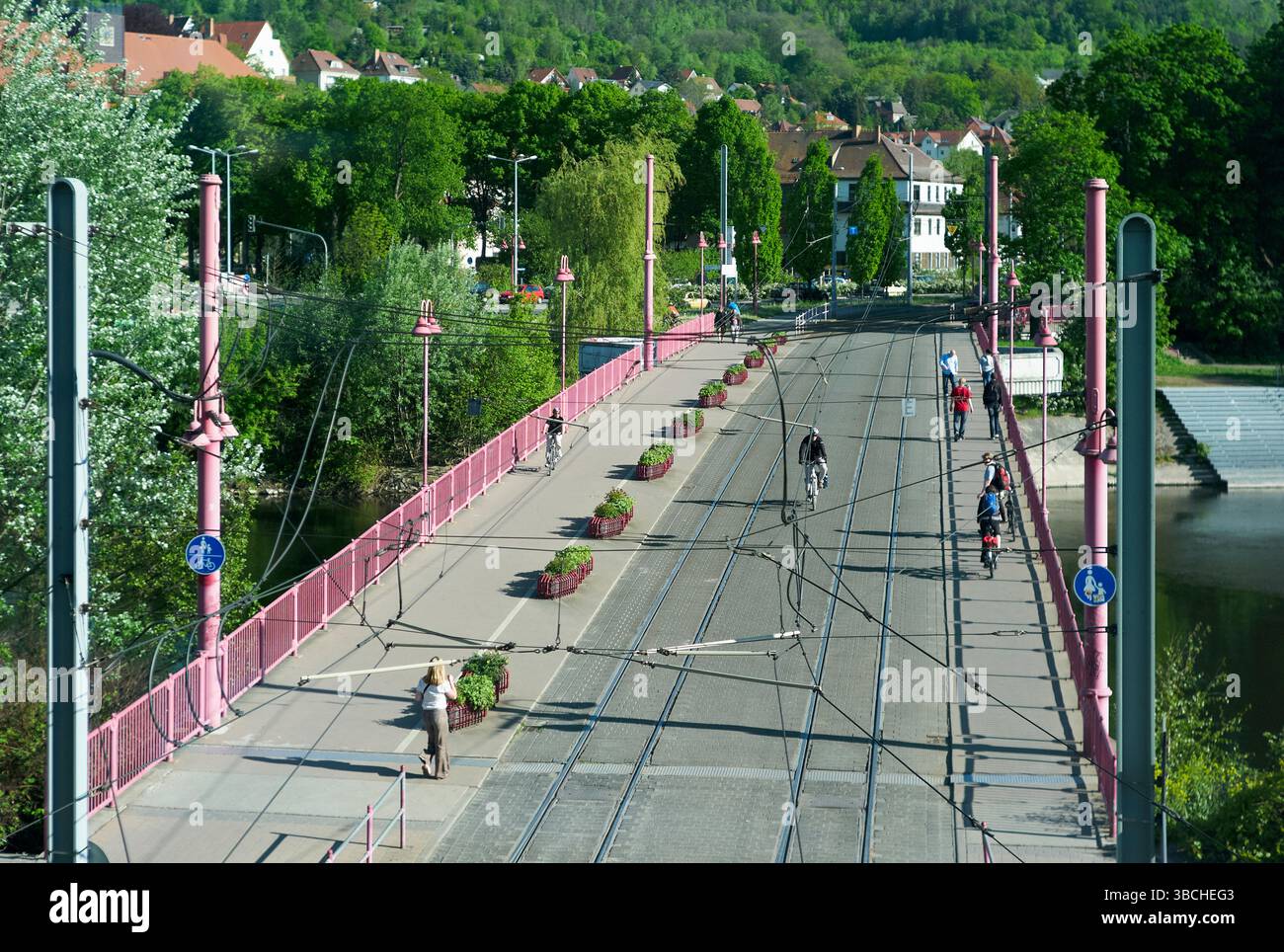 Pont de la ville avec des voies de tramway, bordé de lampadaires et de verdure luxuriante entourant la région. Autriche Banque D'Images