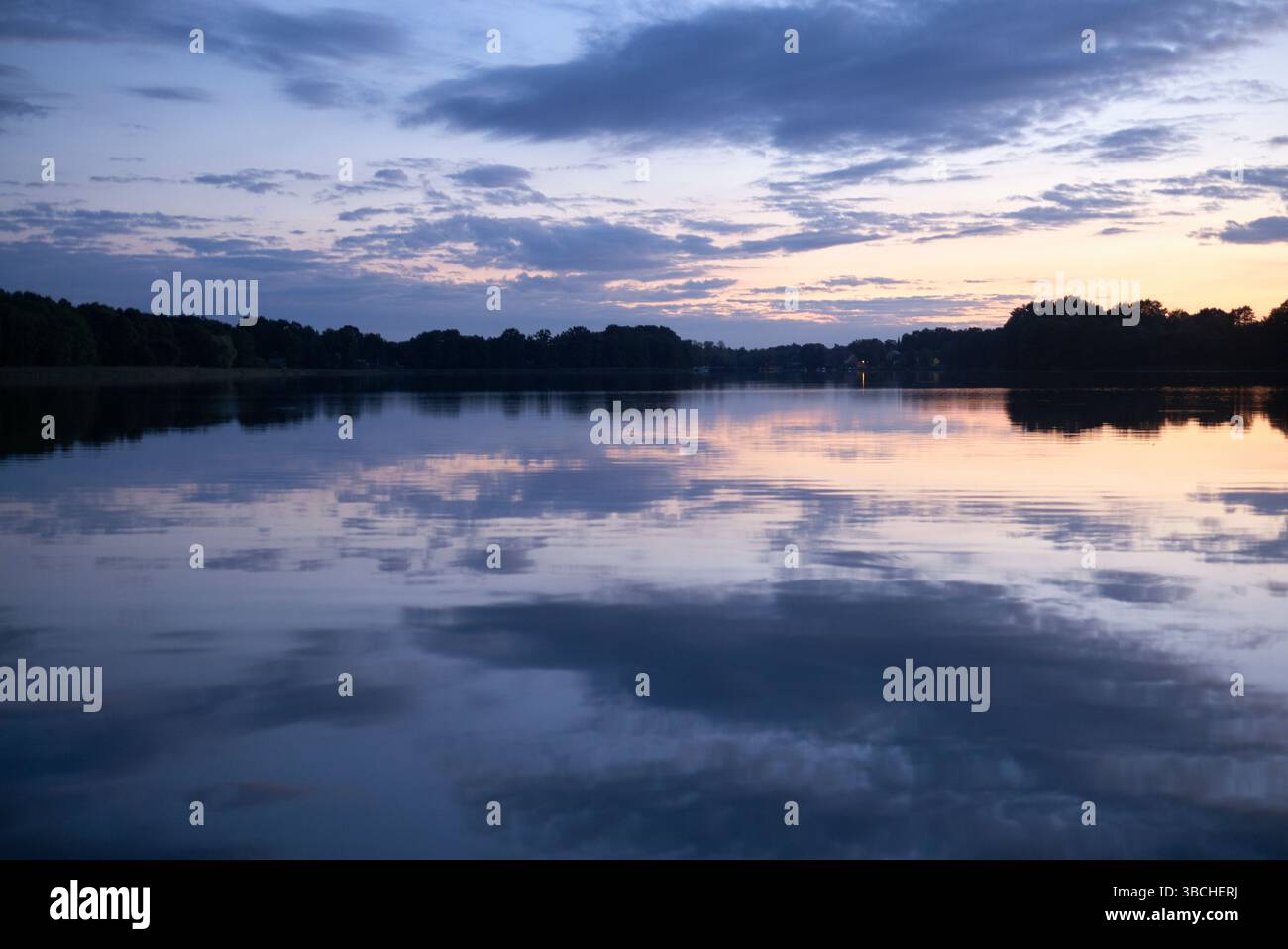 Lac tranquille avec des reflets de coucher de soleil et horizon serein. Plateau du lac de Mecklenburg, Allemagne Banque D'Images