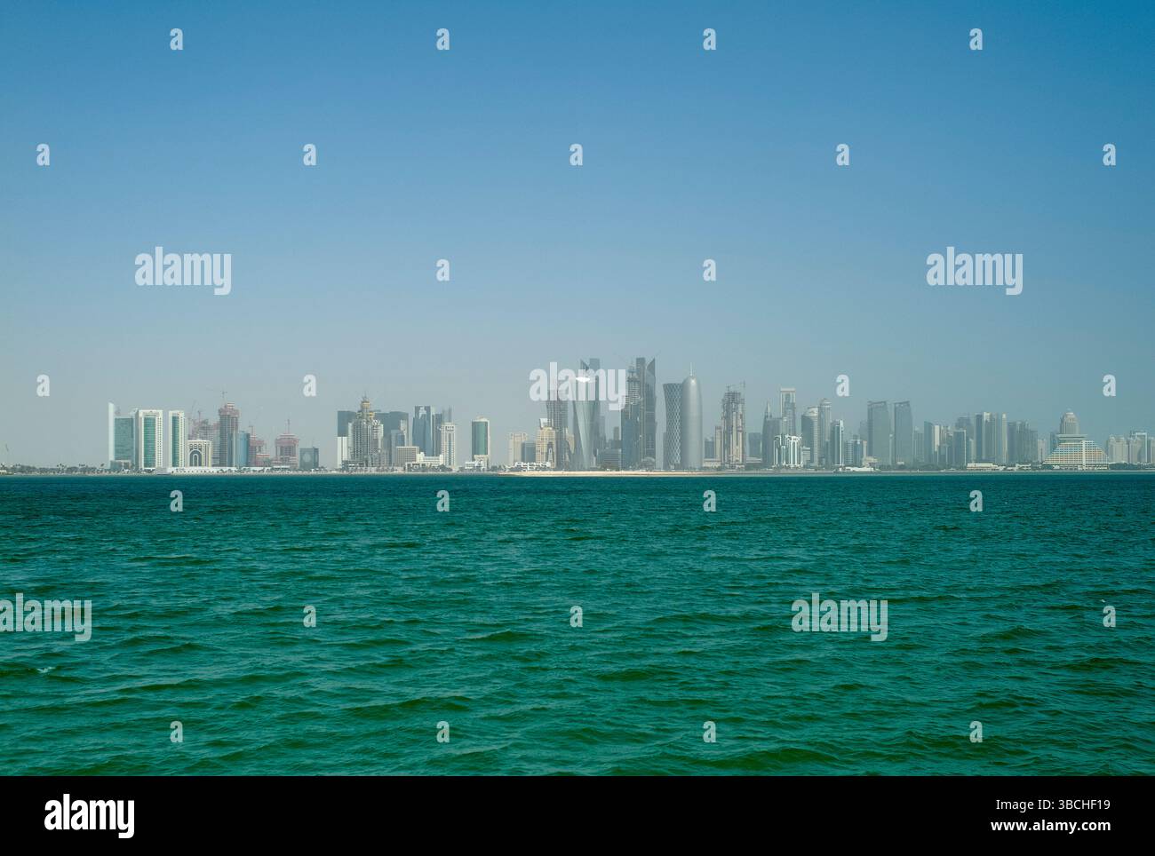 Gratte-ciel d'une ville moderne reflétée dans la mer turquoise calme sous un ciel bleu clair. Qatar Banque D'Images
