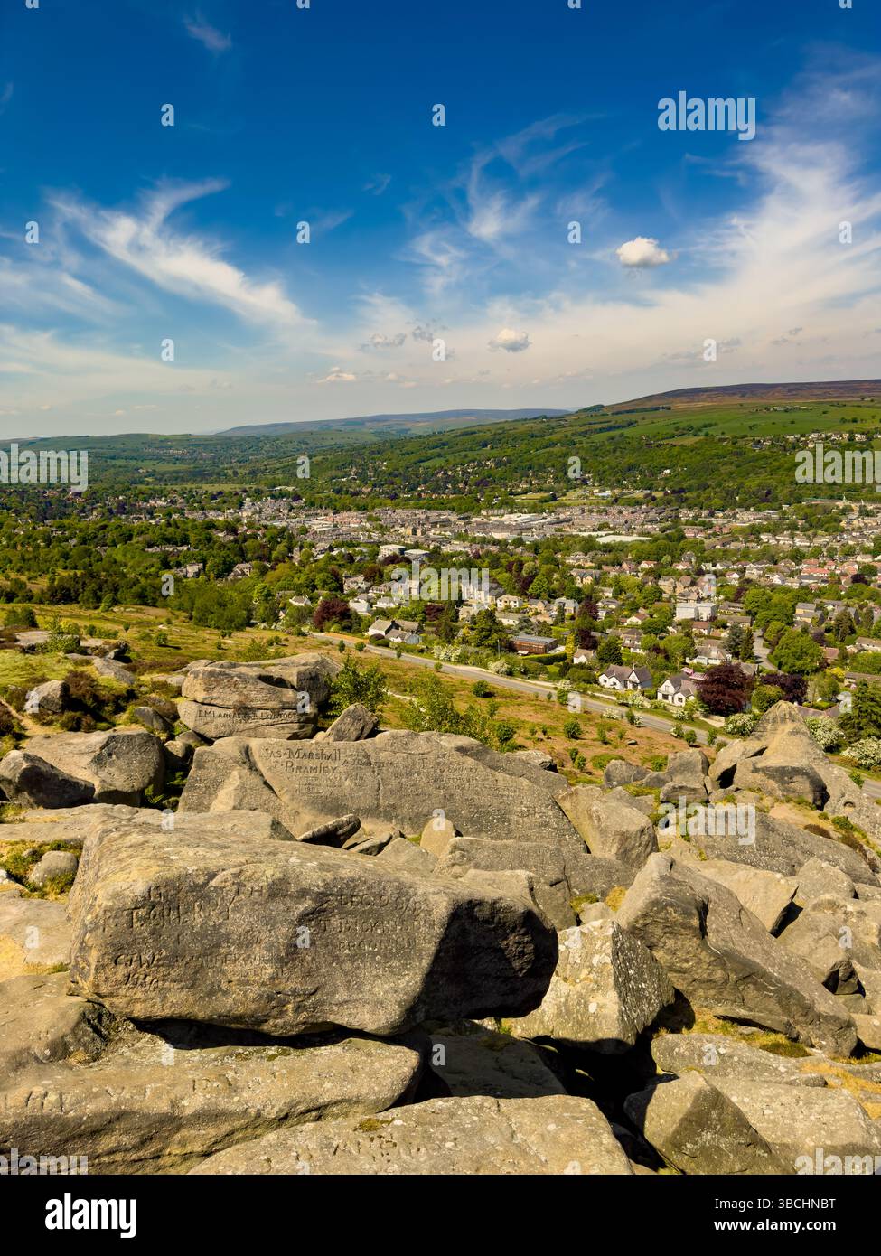Vue sur Ilkley depuis les rochers de vache et de veau, avec graffiti sculptés historiques visibles sur les rochers du premier plan. West Yorkshire. ROYAUME-UNI Banque D'Images